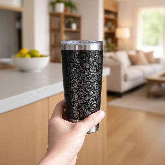 Hand holding a black floral-patterned tumbler in a kitchen setting