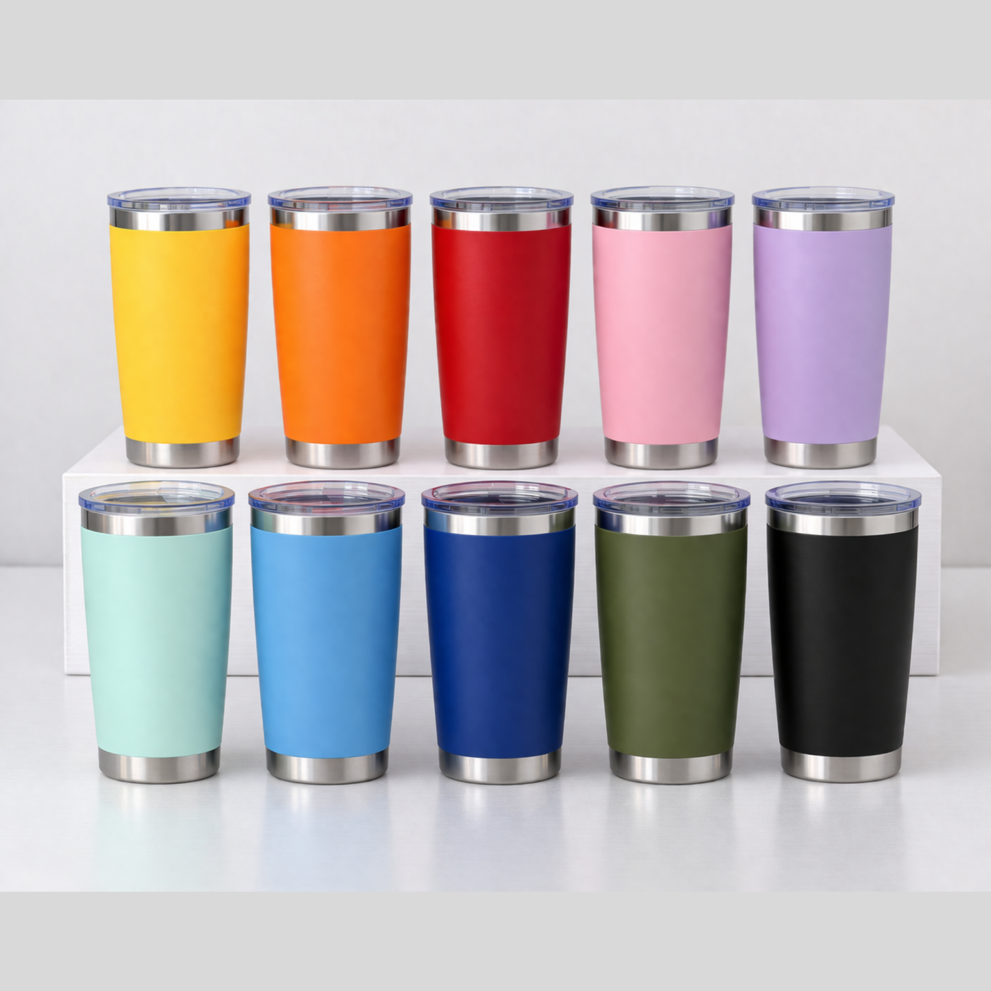 Row of colorful insulated tumblers with silver lids on a white surface.